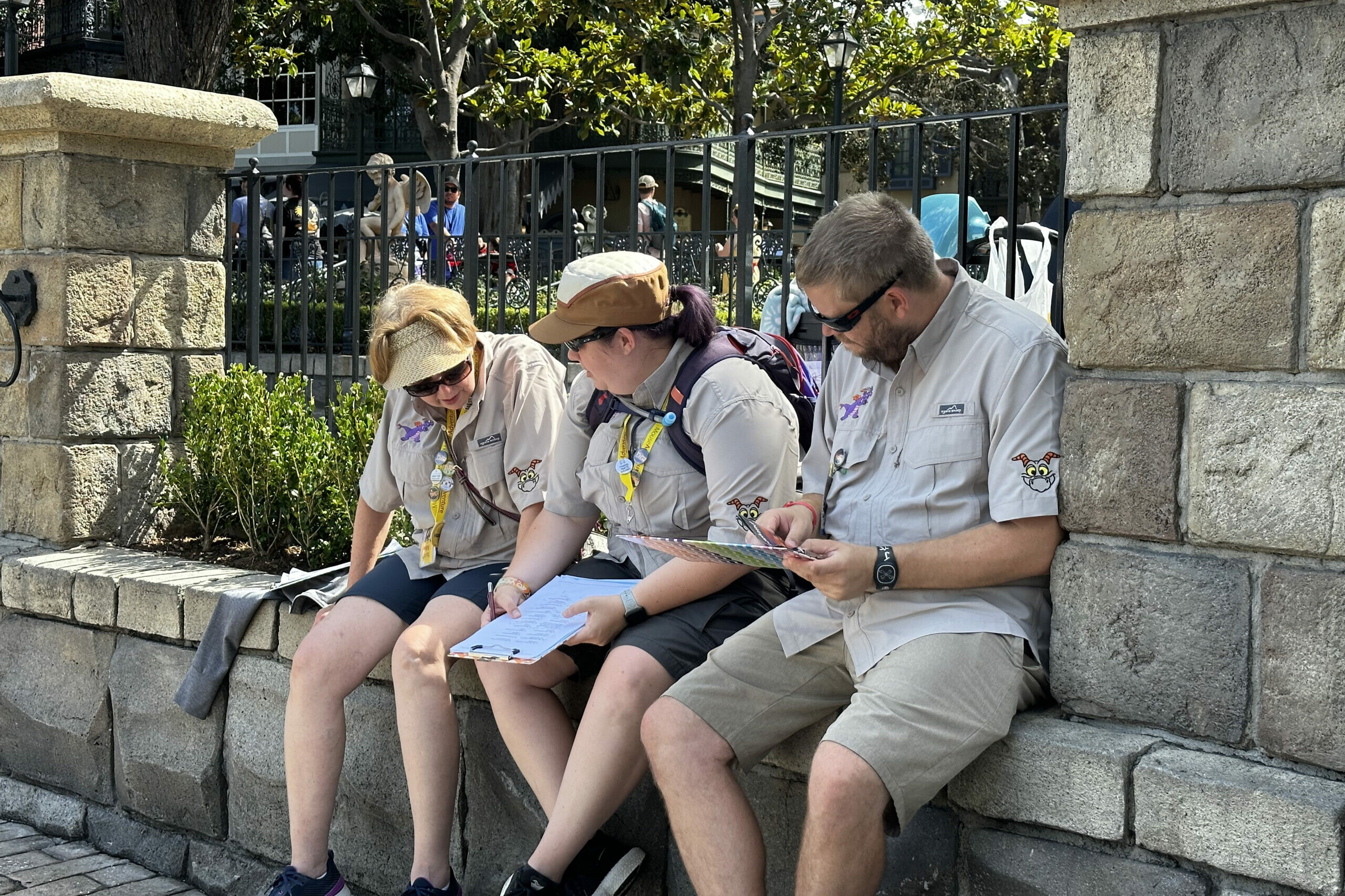 Three players sit on a stone wall working on puzzles